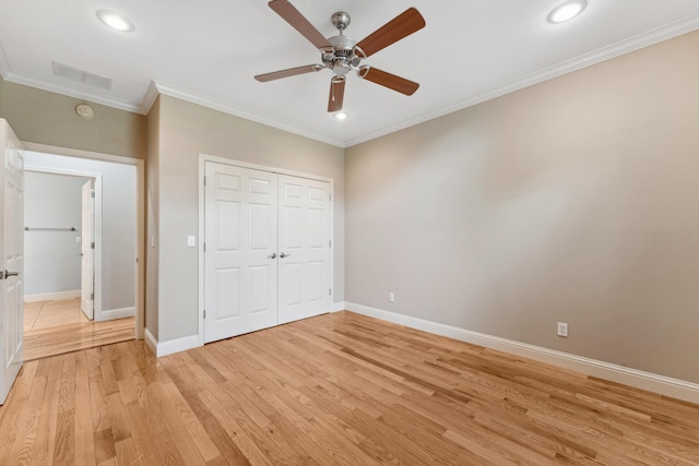 unfurnished bedroom with light wood-style flooring, visible vents, baseboards, a closet, and crown molding