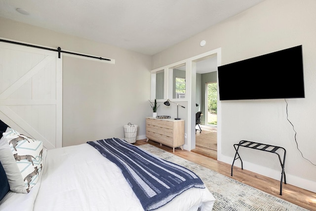 bedroom with wood finished floors, baseboards, and a barn door