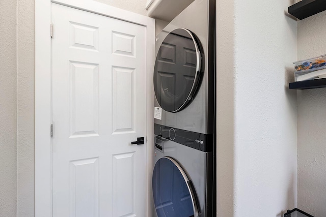 laundry room featuring laundry area, a textured wall, and stacked washing maching and dryer