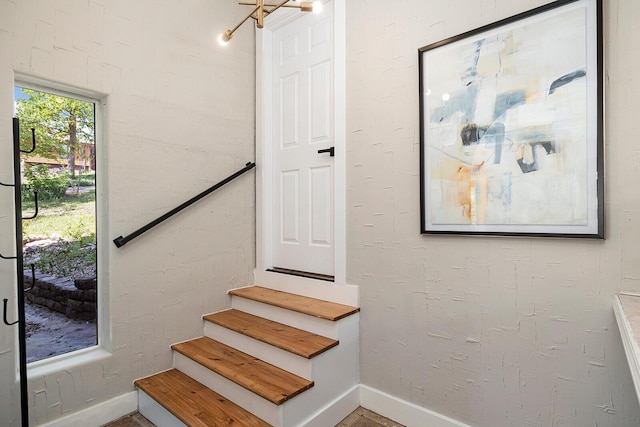 stairway featuring a textured wall and baseboards