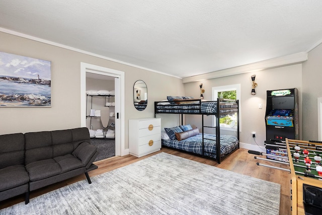 bedroom with a textured ceiling, ornamental molding, and wood finished floors