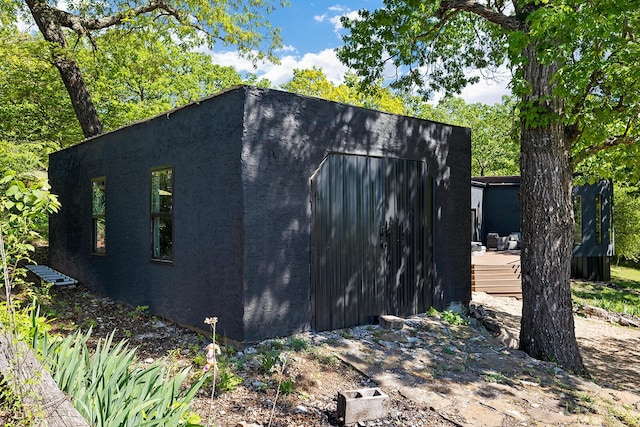 view of side of home with an outdoor structure and stucco siding