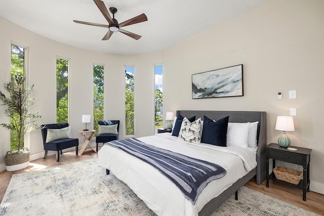 bedroom with ceiling fan, wood finished floors, and baseboards