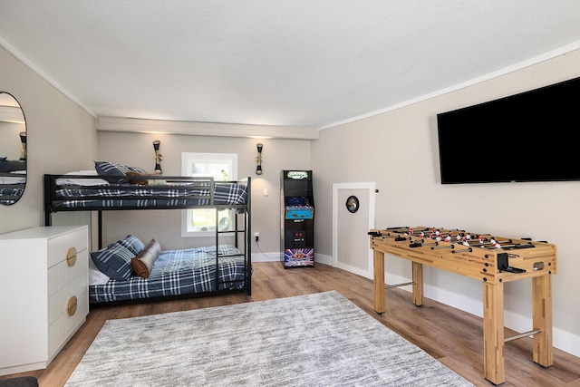 bedroom with baseboards, wood finished floors, and crown molding