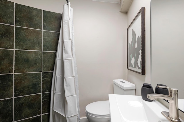 bathroom featuring toilet, a shower with curtain, and a sink