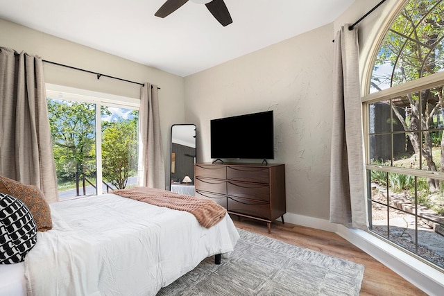 bedroom with ceiling fan, a textured wall, baseboards, and wood finished floors