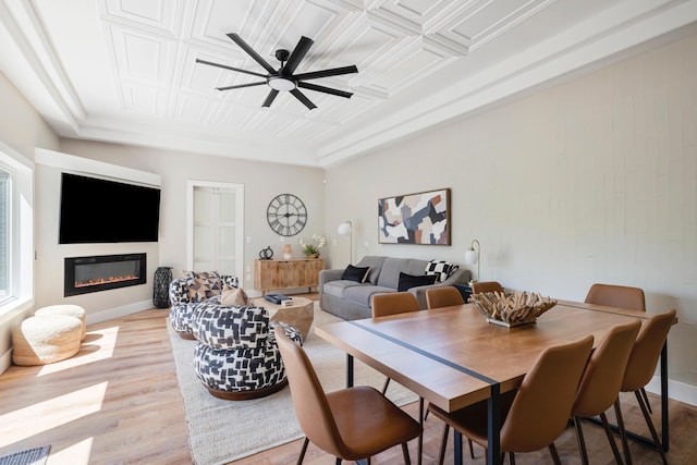 dining space featuring visible vents, light wood-style flooring, a glass covered fireplace, and an ornate ceiling