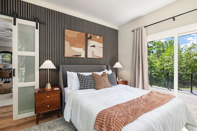 bedroom with a barn door and wood finished floors