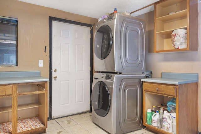 washroom featuring stacked washer and dryer, laundry area, and light tile patterned flooring