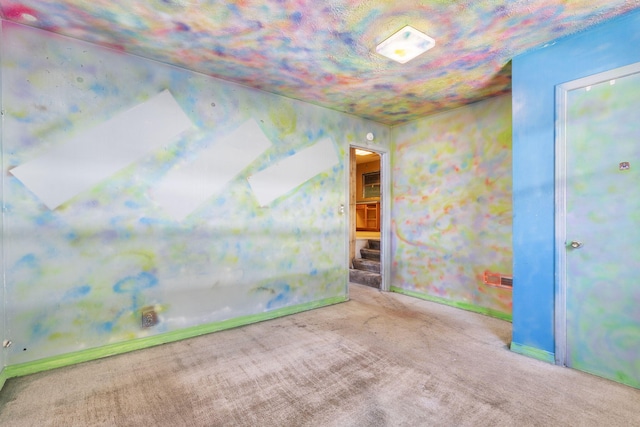 spare room featuring stairway, carpet flooring, and baseboards