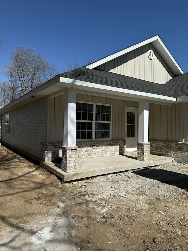 rear view of house featuring roof with shingles