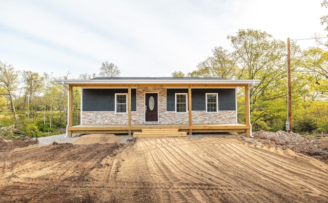 ranch-style home with a porch and stone siding