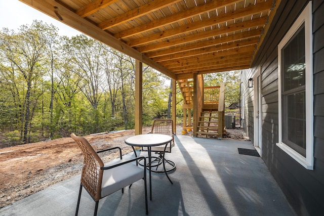 view of patio featuring outdoor dining space, central air condition unit, and stairs