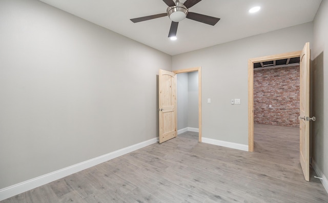 unfurnished bedroom with ceiling fan, baseboards, brick wall, light wood-type flooring, and recessed lighting