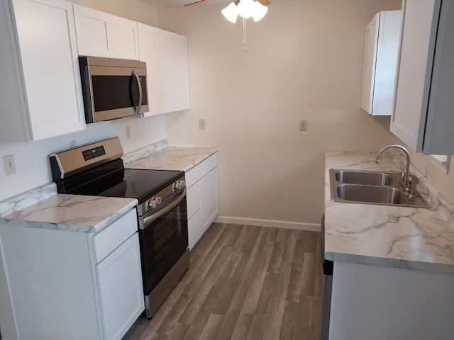 kitchen with white cabinets, light wood-style flooring, stainless steel appliances, and a sink