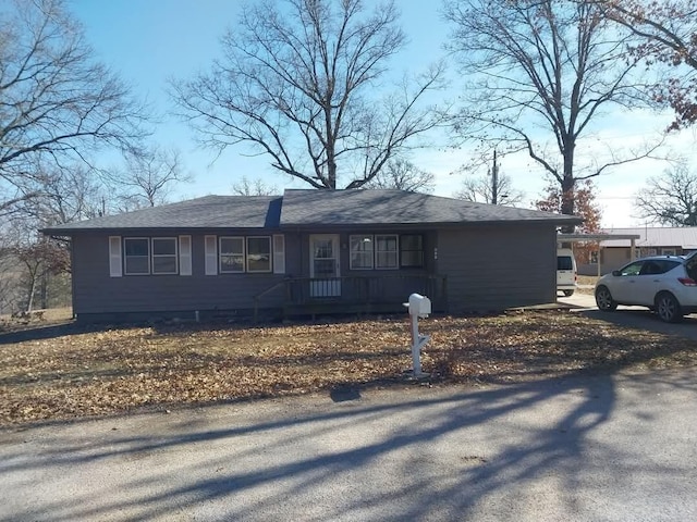 ranch-style home featuring aphalt driveway and roof with shingles