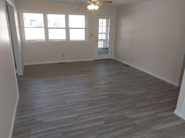 unfurnished room featuring a ceiling fan, dark wood-style flooring, and baseboards