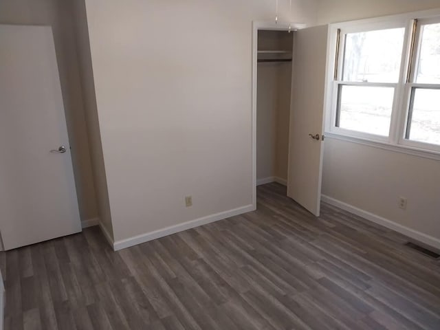 unfurnished bedroom featuring a closet, visible vents, dark wood finished floors, and baseboards