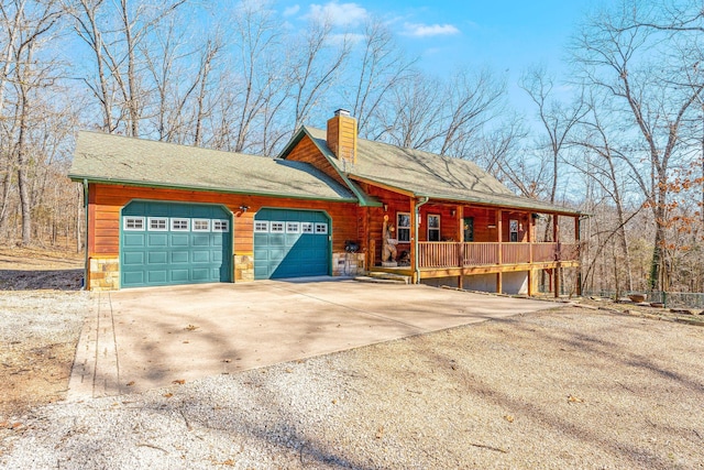 view of home's exterior featuring an attached garage, covered porch, driveway, stone siding, and a chimney