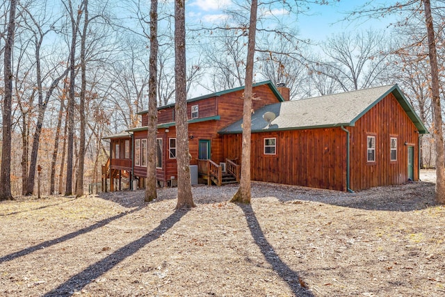 back of property featuring a shingled roof and a chimney