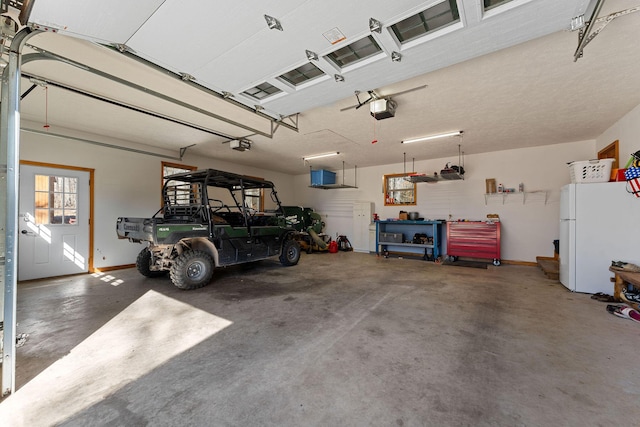 garage featuring a garage door opener, freestanding refrigerator, and baseboards