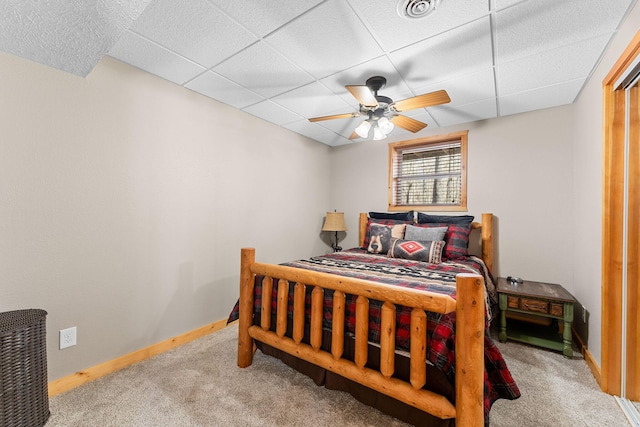 carpeted bedroom with baseboards, visible vents, ceiling fan, and a drop ceiling