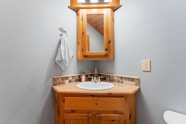 half bath with toilet, vanity, and a textured wall