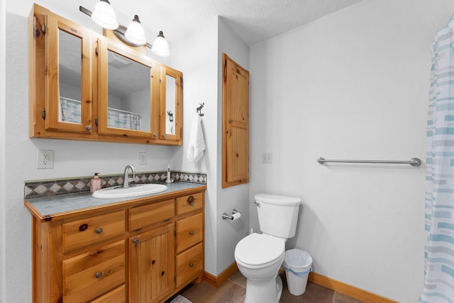 bathroom featuring baseboards, toilet, tile patterned floors, a textured ceiling, and vanity