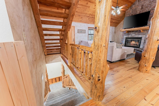 stairway with wooden ceiling, a fireplace, a ceiling fan, vaulted ceiling, and wood-type flooring