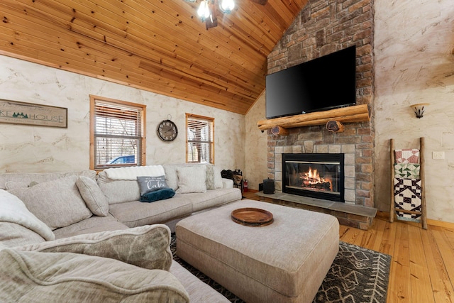 living room with wood ceiling, vaulted ceiling, hardwood / wood-style floors, and a stone fireplace