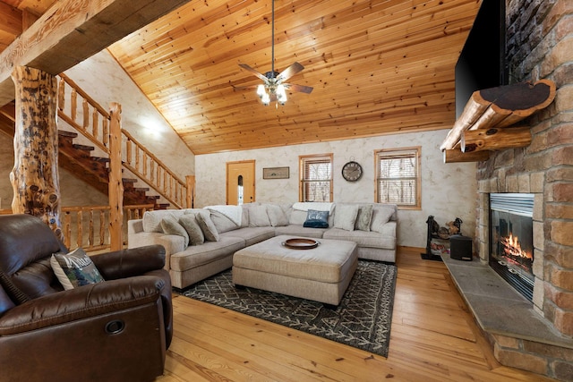 living area featuring high vaulted ceiling, a stone fireplace, wood ceiling, stairs, and hardwood / wood-style floors