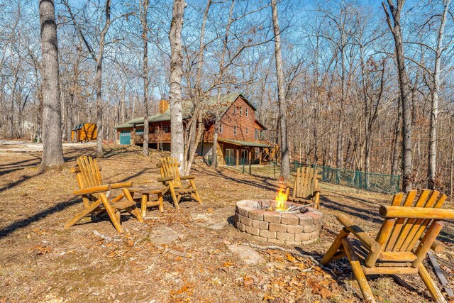 view of yard featuring a fire pit, a forest view, a deck, and fence