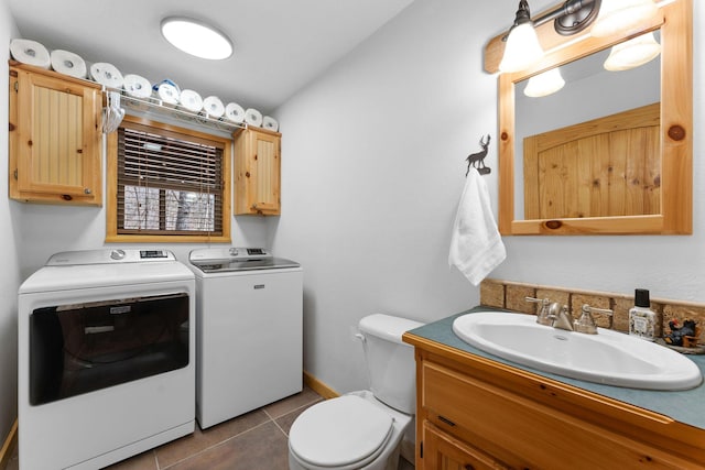 bathroom featuring washer and clothes dryer, toilet, vanity, tile patterned flooring, and baseboards