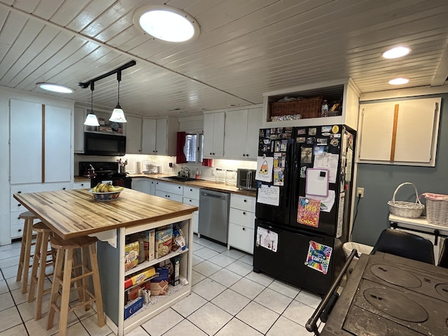 kitchen featuring light tile patterned floors, black appliances, a sink, and wood counters