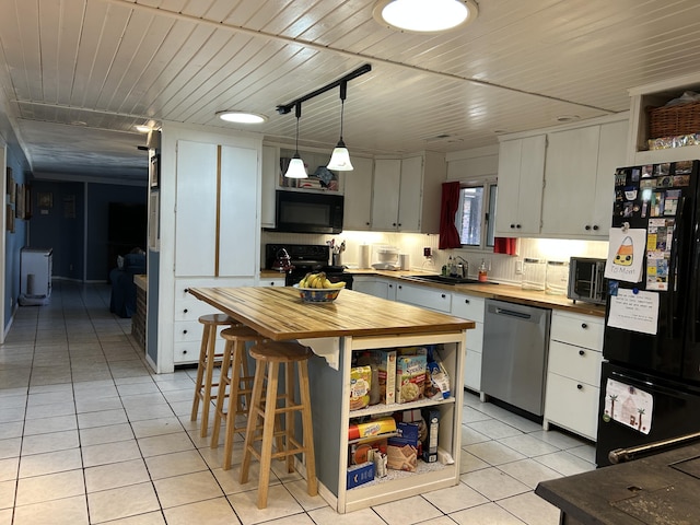 kitchen with butcher block countertops, light tile patterned flooring, a sink, and black appliances