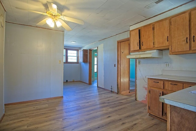 kitchen with light wood finished floors, light countertops, brown cabinetry, ceiling fan, and under cabinet range hood