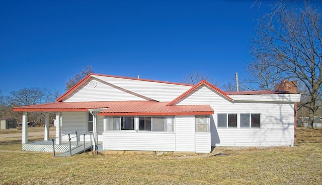 back of property with metal roof, a yard, and a chimney