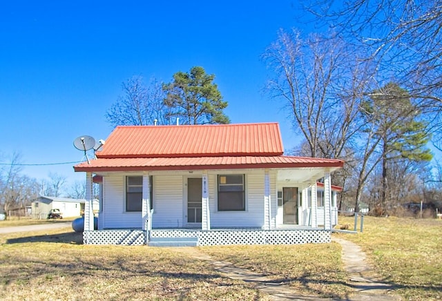 farmhouse inspired home with metal roof, a porch, and a front yard