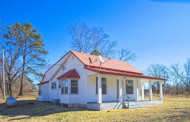 view of front of home featuring covered porch, central AC unit, metal roof, and a front yard