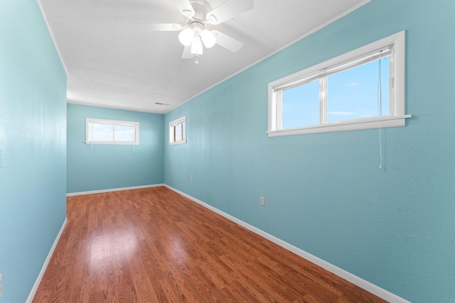 empty room with a ceiling fan, baseboards, and wood finished floors