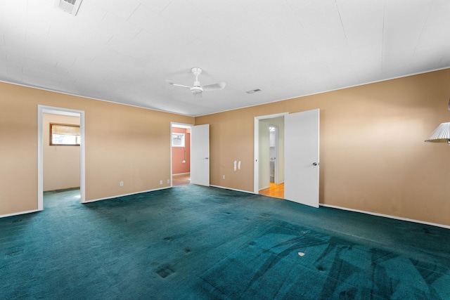 carpeted spare room featuring visible vents, a ceiling fan, and baseboards