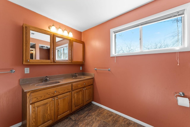 bathroom featuring double vanity, a sink, and baseboards