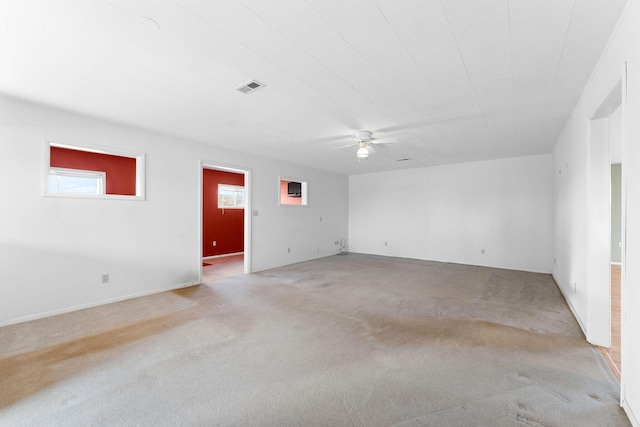 empty room featuring ceiling fan, carpet floors, and visible vents