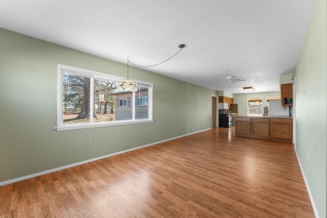 unfurnished living room with wood finished floors, a ceiling fan, and baseboards