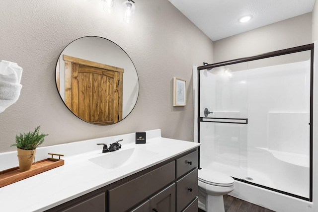 full bath featuring toilet, a stall shower, wood finished floors, and vanity