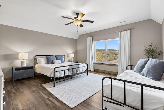 bedroom with lofted ceiling, dark wood-style flooring, visible vents, and baseboards