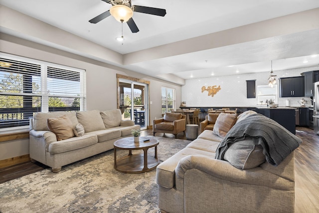 living room featuring wood finished floors, a ceiling fan, and baseboards