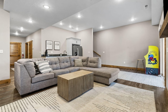 living area featuring baseboards, visible vents, stairs, light wood-type flooring, and recessed lighting