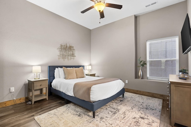 bedroom with a ceiling fan, visible vents, baseboards, and wood finished floors