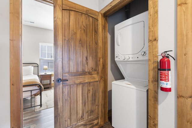 laundry area featuring laundry area, visible vents, stacked washer / drying machine, and wood finished floors